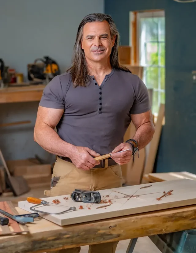 Woodworker at his bench holding a carving tool