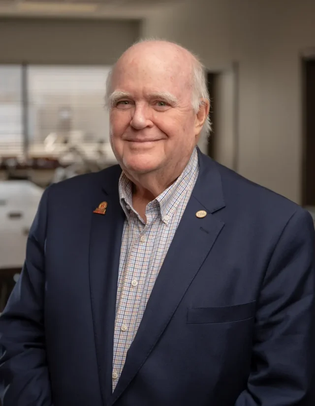 Older man in a navy blazer and checked shirt in an office