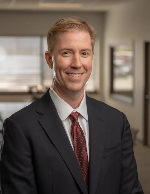 Man in a dark suit and red tie in an office