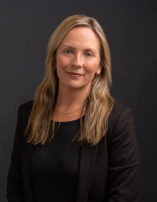 Woman with long hair in a black blazer, studio headshot