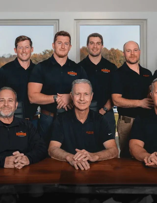 Nine-person company team in matching polos at a boardroom table