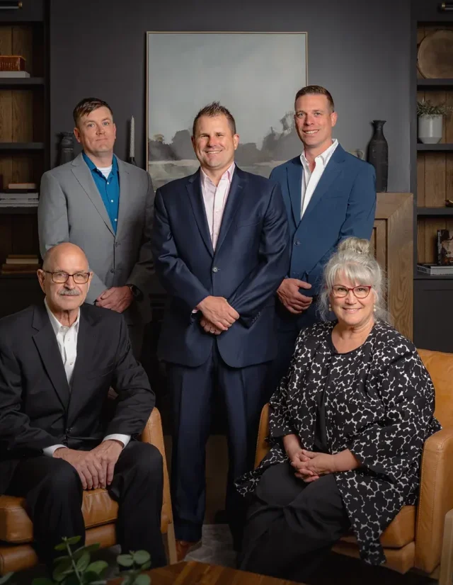 Five-person leadership team around two leather chairs