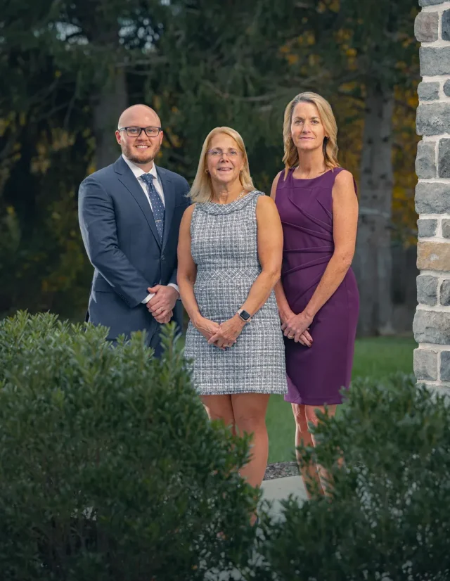 Three colleagues standing beside a stone wall