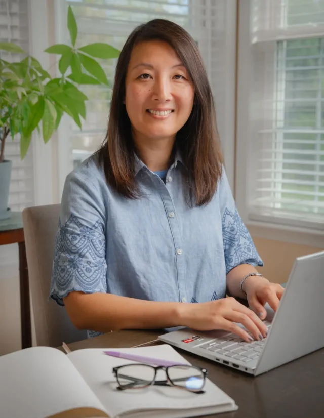 Woman at a desk with a laptop and notebook