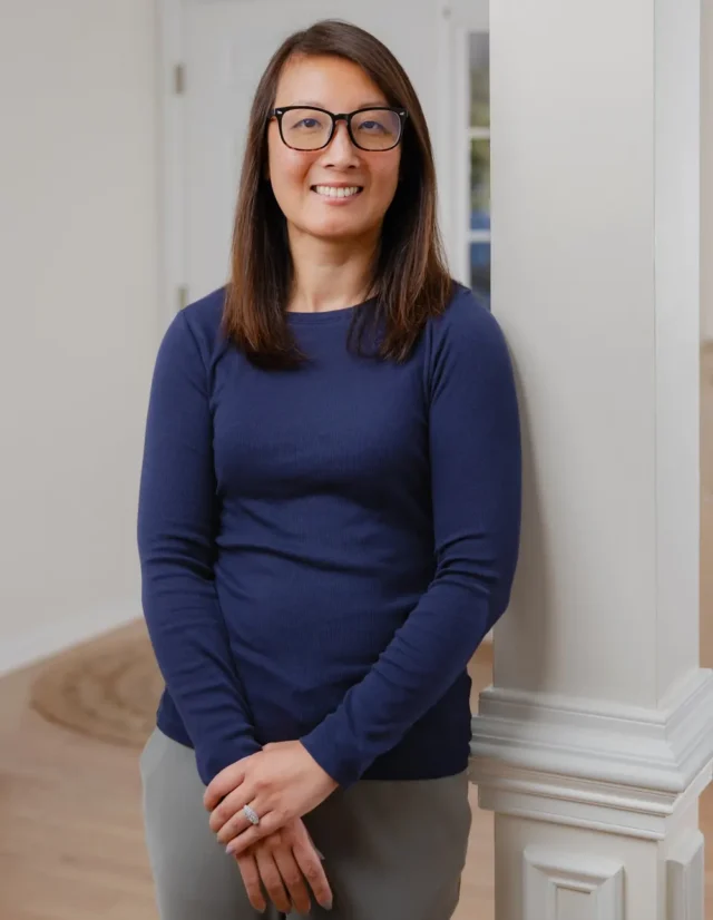 Woman in glasses leaning on a white column at home